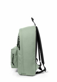 Sac à dos en tissu vert avec une finition mate, de forme rectangulaire, avec des sangles noires et une poche externe. Il dispose de bretelles ajustables et d'accents à cordon.