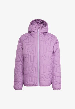 Mladić se smiješi, nosi ljubičastu prošivenu jaknu i sunčane naočale na glavi, držeći nehrđajući čelični kamperski lonac.