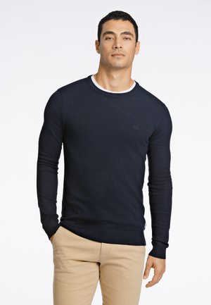 Marineblauer Pullover mit Rundhalsausschnitt und langen Ärmeln, mit gerippten Bündchen und Saum, mit einem dezenten Logodetail auf der Brust. Glatte Strickstruktur.