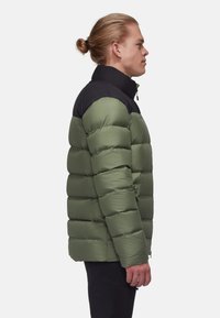 Vadderad jacka i olivgrön med svart krage, med dragkedja fram och sidofickor. Slät textur med horisontell quiltad design.