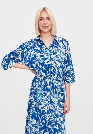 Niebieska i biała sukienka w kwiaty z krótkim rękawem, zapinana na guziki, z elastyczną talią i warstwowym dołem, wykonana z lekkiego materiału.