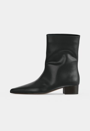 Bottine en cuir noire avec talon bloc bas et bout pointu, finition lisse et design légèrement décontracté.