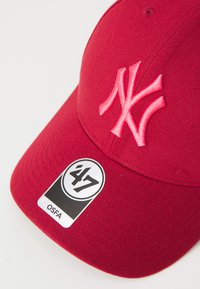 Červená bavlnená baseballová čiapka s vyšívaným ružovým logom NY, zakriveným okrajom a čierno-bielou nálepkou označenou "47 OSFA."