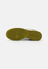 Sole di scarpa Nike in gomma verde con modelli di battistrada circolari e lineari; presenta un logo centrale. Bordi lisci con grip testurizzato.