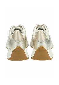 Le sneakers presentano una parte superiore in tessuto crema con accenti in oro metallico, un colletto imbottito e una suola in gomma marrone con una finitura texturizzata.