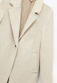 Cappotto in misto lana beige con colletto a punta, chiusura a un bottone e tasca sul petto; texture morbida e design su misura.