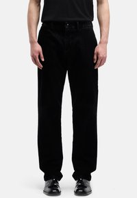 Czarne spodnie sztruksowe o prostym kroju, z zapięciem na guzik i przednimi kieszeniami. Materiał ma prążkowaną fakturę i matowe wykończenie.