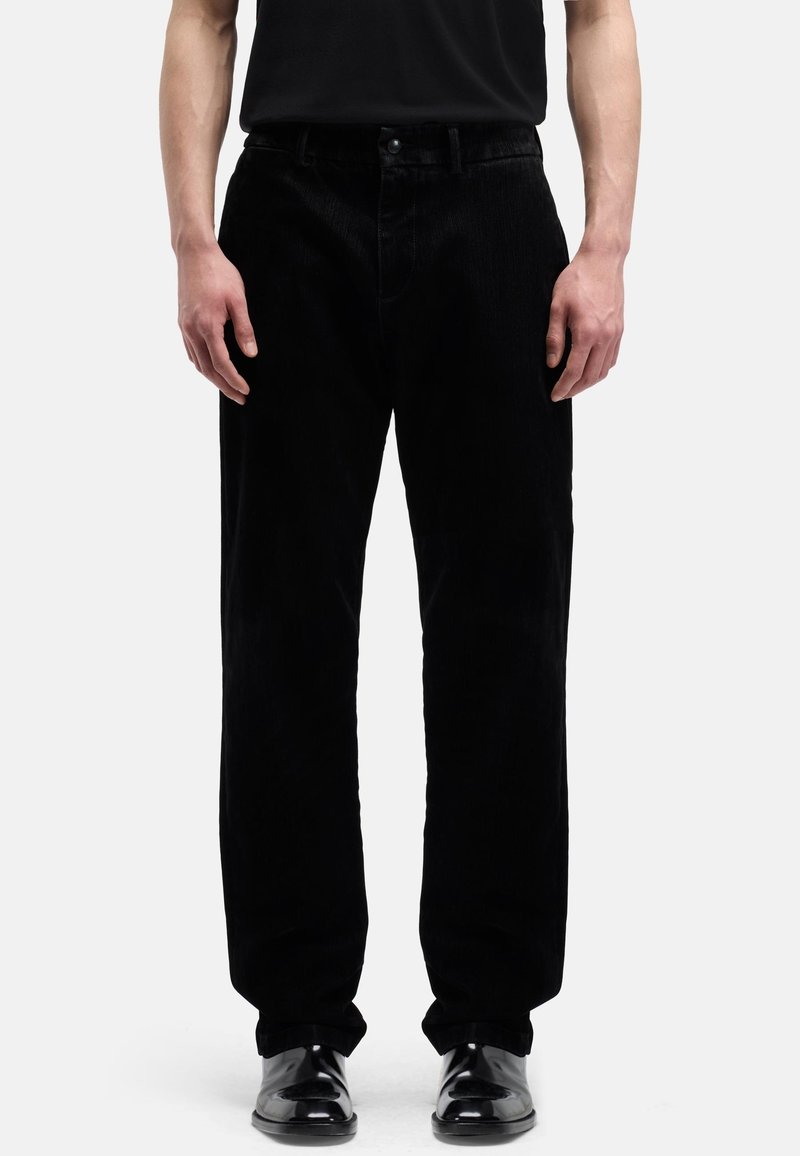Czarne spodnie sztruksowe o prostym kroju, z zapięciem na guzik i przednimi kieszeniami. Materiał ma prążkowaną fakturę i matowe wykończenie.