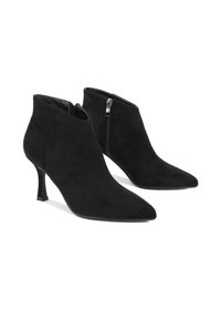 Černé kotníkové boty z broušené kůže s špičatou špičkou a štíhlým vysokým podpatkem, s bočním zipem a měkkou texturou. Kompaktní design pro zvýšení elegance.