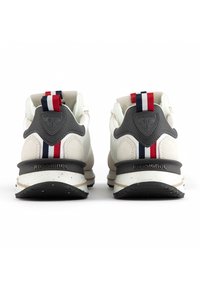 White athletic shoes with gray accents, fabric and mesh upper, textured back support, and multicolored striped heel pull tabs.