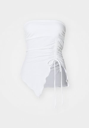 Haut blanc sans bretelles avec une texture froncée, un ourlet asymétrique et un détail de cordon ajustable sur le côté. Tissu lisse et extensible.