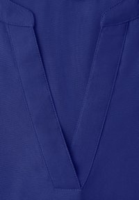 Gros plan sur un tissu bleu profond sur mesure avec une couture nette en forme de V sur le revers, mettant en valeur des coutures précises et la texture.