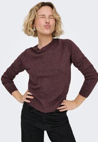 Mörk vinröd stickad tröja med långa ärmar och rund halsringning. Mjuk textur, figursydd stil, kombinerad med svart byxa med hög midja.