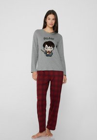 Camiseta de pijama de manga larga gris con un gráfico de Harry Potter. Combinada con pantalones de pijama de cuadros rojos y negros, de tejido suave y corte relajado.