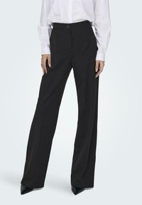 Schwarze weite Hosen mit hoher Taille und einem vorderen Knopfverschluss. Aus glattem Stoff mit maßgeschneiderten Nähten und einer klaren Silhouette.