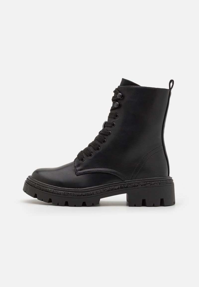 Botte de combat en cuir noir avec semelle épaisse à crampons, fermeture à lacets à l’avant, hauteur à la cheville et languette à l’arrière sur fond blanc.