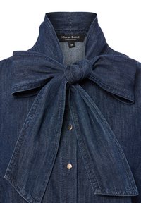 Camicia di denim blu scuro, caratterizzata da un grande papillon al collo, chiusura a bottoni e una texture morbida con accenti hardware contrastanti.