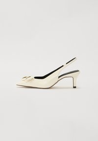 Krémové slingback opätky s špicatou špičkou, ktoré majú veľkú dekoratívnu mašľu na priehlavku a štíhly, nízky opätok. Hladký povrch.