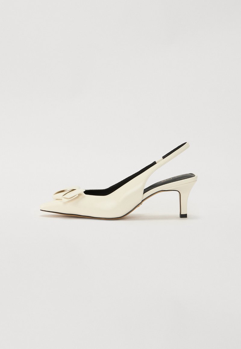 Krémové slingback opätky s špicatou špičkou, ktoré majú veľkú dekoratívnu mašľu na priehlavku a štíhly, nízky opätok. Hladký povrch.