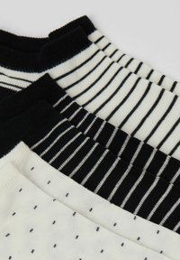 Čtyři páry ponožek ze směsi bavlny, které mají černobílé pruhy, puntíky a žebrované manžety. Různé barevné vzory vytvářejí kontrast.