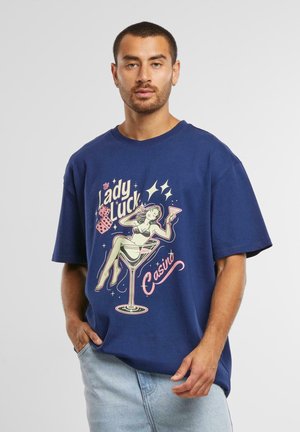 Navy blue oversized t-shirt made of cotton, featuring a graphic of a woman in a martini glass with decorative text and accents.