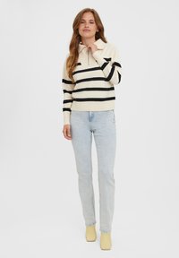 Cream and black striped pullover with a zip collar, paired with light blue slim-fit jeans and yellow block-heel boots.