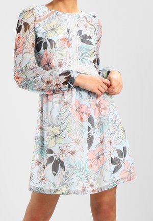 Vestido floral azul claro con mangas largas abullonadas, detalles de encaje en el pecho y una falda fluida, usado por una persona de pie.