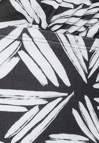 Svart tyg med djärva vita bladmönster i penseldragseffekter, som visar en slät textur och väldefinierade designelement.