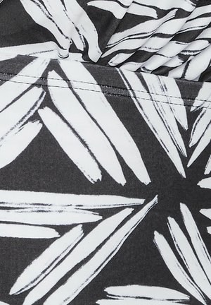 Tissu noir avec de grands motifs de feuilles blanches aux effets de coups de pinceau, présentant une texture lisse et des éléments de design bien définis.