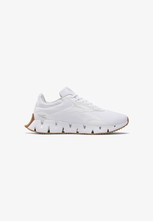 White athletic shoe with a mesh upper, padded collar, and textured rubber sole featuring cut-out details. Brown outsole for traction.