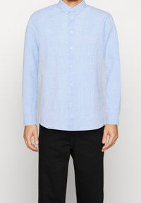 Camicia azzurro chiaro a maniche lunghe con bottoni, realizzata in tessuto testurizzato, con colletto button-down e bottoni perlacei. Vista frontale.