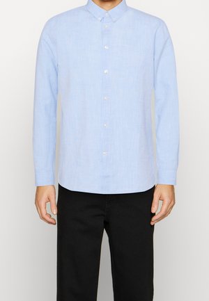 Ljusblå långärmad skjorta med knappar, tillverkad av texturerat tyg, med en button-down krage och pärlemorknappar. Sedd framifrån.