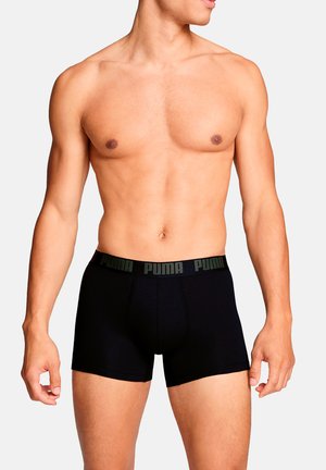 Schwarze Boxershorts aus weichem Stoff, mit einem kontrastierenden grünen elastischen Bund mit "PUMA"-Logo. In mittlerer Oberschenkellänge geschnitten.