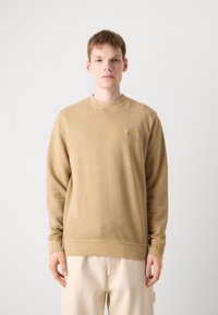 Sweatshirt de algodão bege com decote redondo, mangas longas e um acabamento texturizado, apresentando um pequeno rótulo da marca no lado esquerdo do peito.