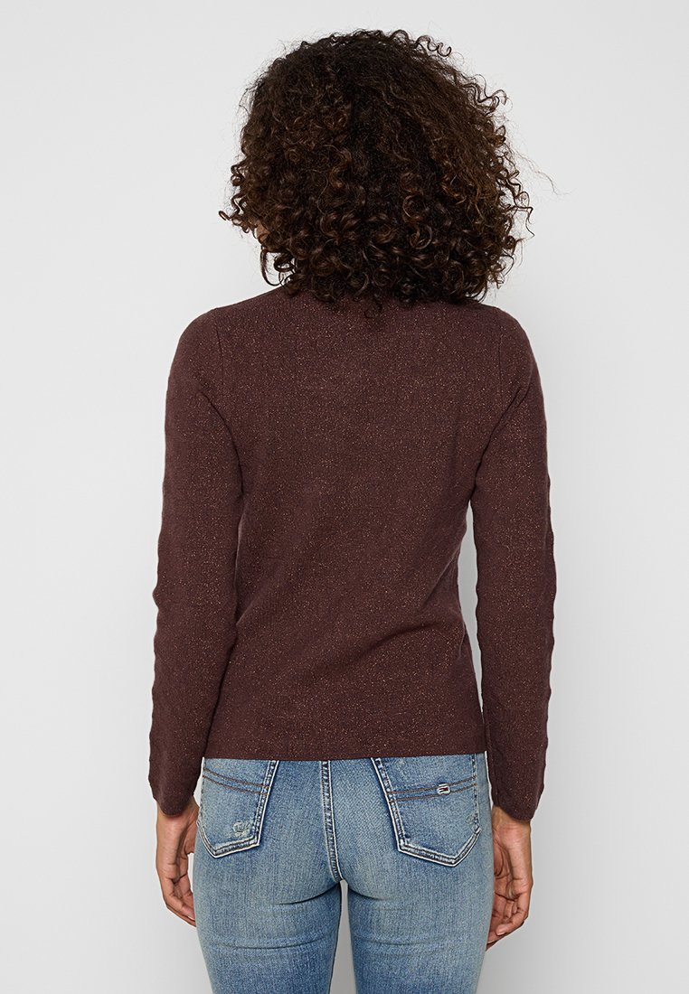 Bruin, lange mouwen trui met een gestructureerde afwerking, met een getailleerd ontwerp. Draagt over lichtblauwe jeans, met een eenvoudige achterkant.