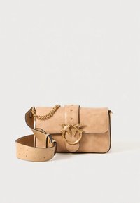 Tan leather crossbody bag with a flap closure, gold hardware, a chain accent, and adjustable strap featuring stud details.