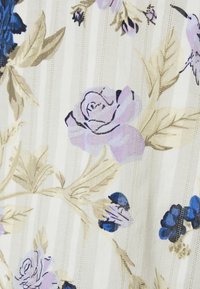 Tissu beige avec des motifs floraux violet clair et bleu, comprenant des roses et des feuilles sur un fond à rayures verticales subtiles.