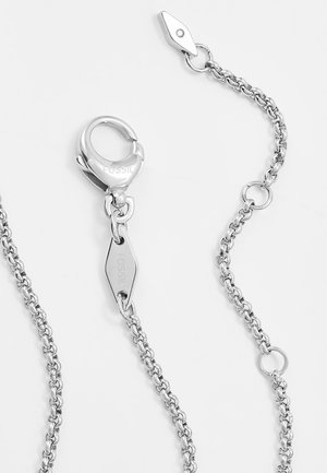 Collier chaîne ton argent avec fermoir homard, étiquettes de marque Fossil et plusieurs maillons ronds sur fond blanc.