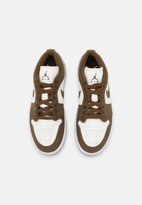 Paire de baskets Nike Air blanches et marron avec des lacets marron, vues de dessus sur un fond clair uni.