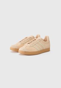 Beige suède sneakers met mesh accenten, voorzien van drie smalle strepen, een ronde neus en een textuur rubberen zool.