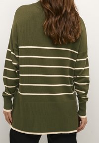 Olijfgroene trui met witte horizontale strepen, voorzien van een ontspannen pasvorm, geribde manchetten en een langere achterkant. Zachte gebreide textuur.