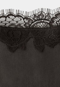 Tissu noir avec une délicate bordure en dentelle florale le long du bord supérieur comprenant un fin filet et des détails pointus.