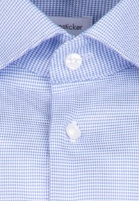Jasnoniebieska koszula w kratę z białymi guzikami i usztywnionym kołnierzykiem. Tkanina ma teksturowany wzór małych kwadratów.