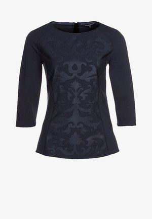 Top blu navy con maniche tre quarti, superficie testurizzata con un sottile motivo damascato, scollatura rotonda e dettaglio con zip sul retro.