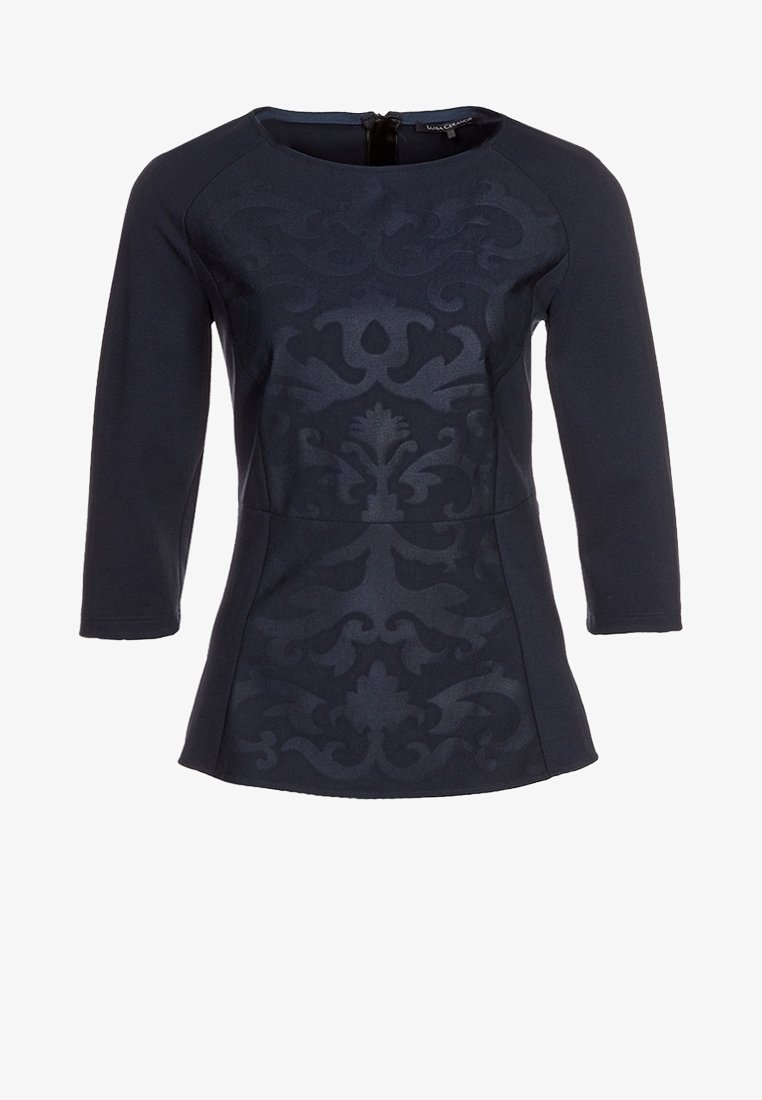 Haut bleu marine avec des manches trois-quarts, surface texturée présentant un motif damassé subtil, décolleté arrondi et détail de fermeture éclair dans le dos.