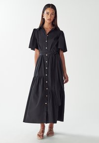 Musta napillinen maxi-mekko, jossa on lyhyet puff-hihat, sidottava vyö, kerroksellinen helma ja kiiltävät napit. Sujuva kangas.