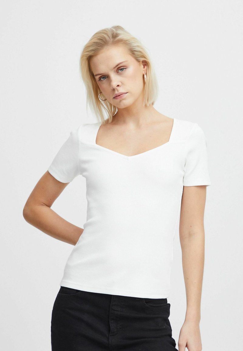 White fitted short-sleeve top with a square neckline, made of ribbed texture fabric. Worn with black pants, featuring a slim silhouette.