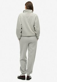 Grijze fleece sweatshirt met hoge kraag en bijpassende joggingbroek; zachte textuur; aansluitende boorden; gedragen met zwarte schoenen.