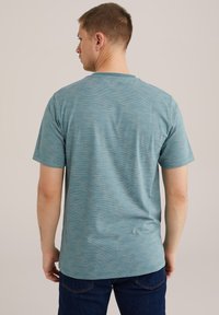 Kortærmet teal T-shirt med en diskret stribet tekstur, rund halsudskæring og en afslappet pasform. Synlig mærkat på den nederste bagside af sømmen.
