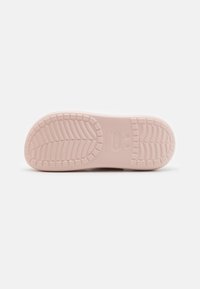 Semelle d'une chaussure Crocs rose clair montrant le motif de la semelle et les indications de taille sur un fond clair uni.